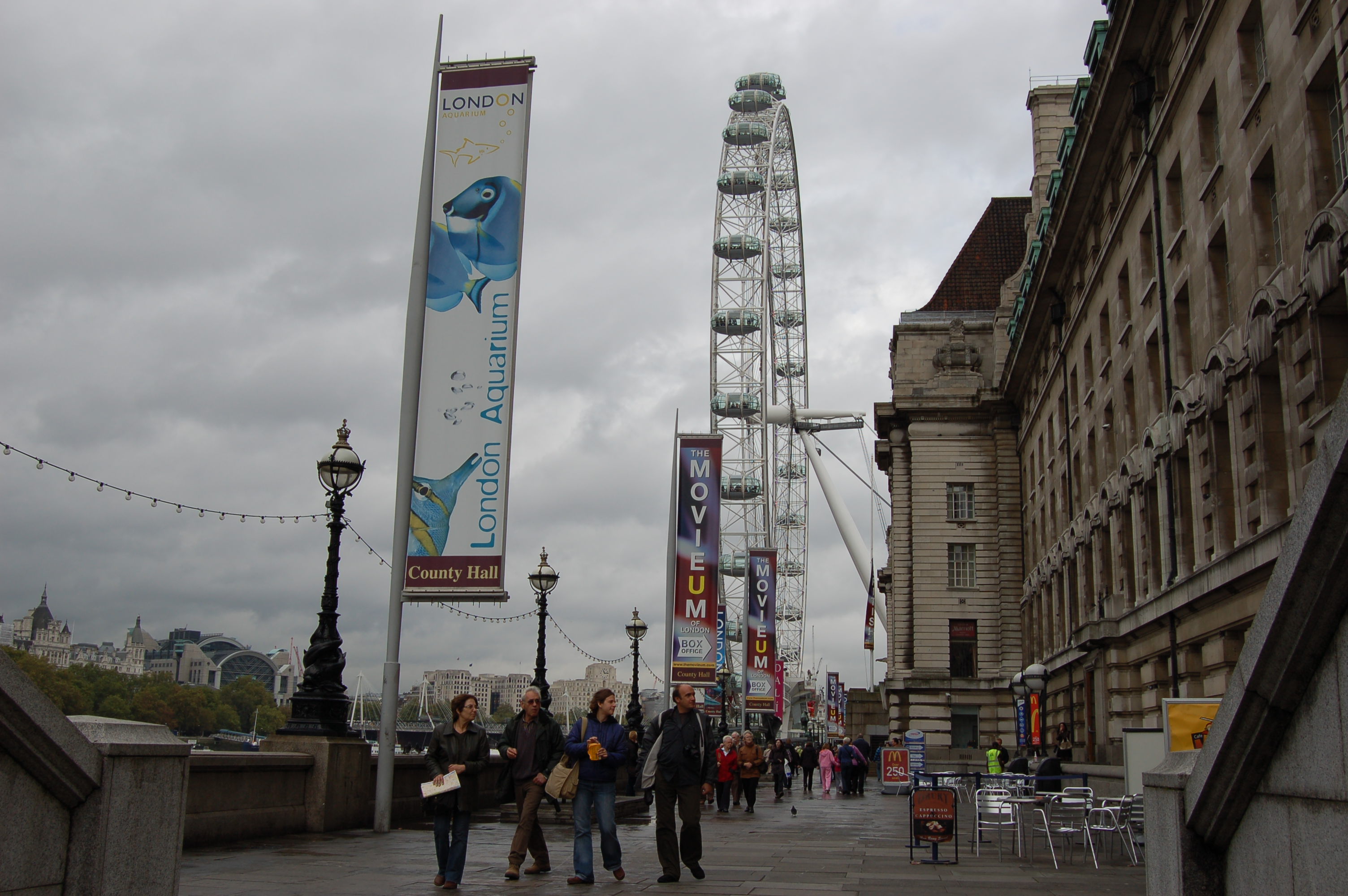 The picture shows colourful banners, including one for the London Aquarium, along the South Bank with the wheel of the London Eye in the background.