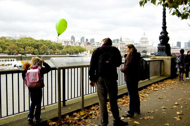 The Thames Path near Tate Modern with a family looking at an interpretative panel by the river.