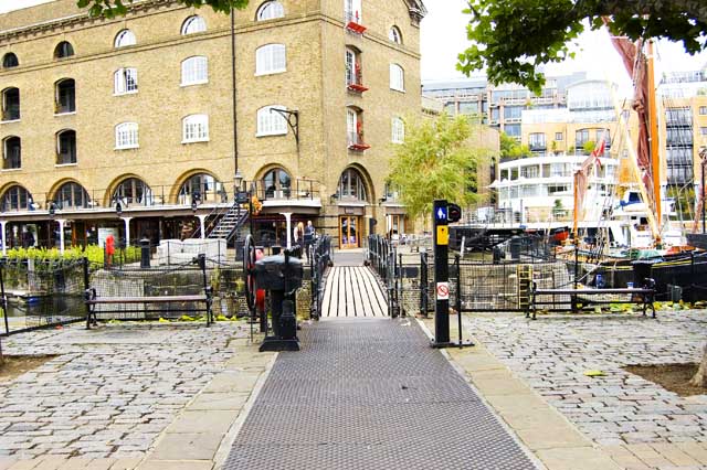 The footbridge, built by Thomas Telford, goes over the dock and retracts to allow boats through. Sailing boats and large vessels are seen in the background.