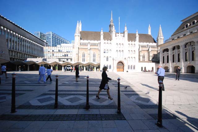 The Gothic Guildhall is shown straight ahead with the modern building of the Art Gallery to the right. They are seen across a square with patterned paving on it.