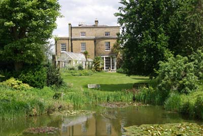 The famous gardens of Myddleton House run down to the pool from the stone 19th century house with its bowed front window.